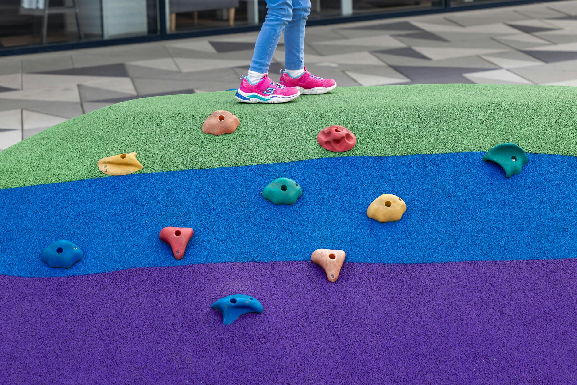 Dziecko bawi się na kolorowej konstrukcji wspinaczkowej na placu zabaw