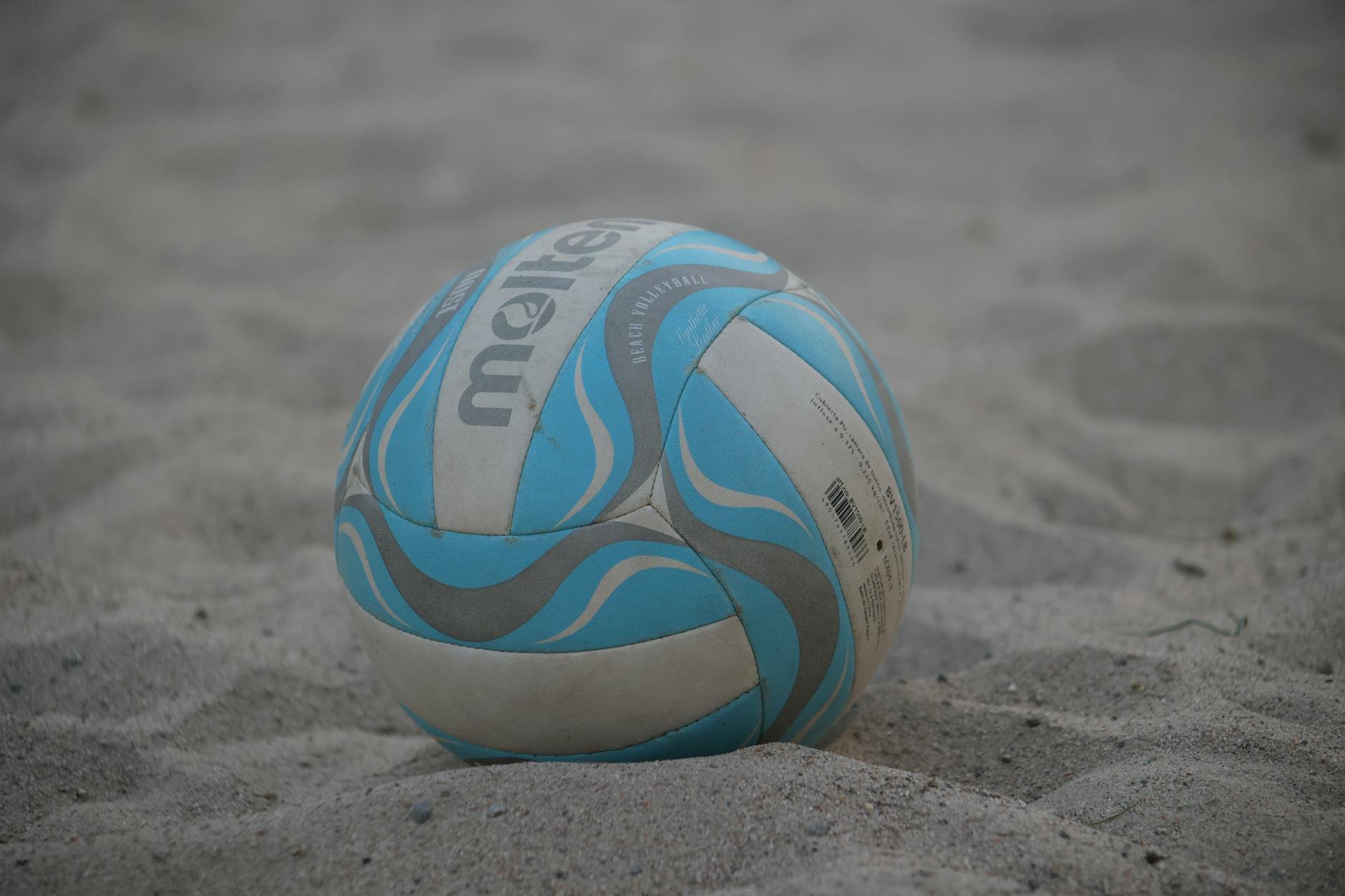 Buty do siatkówki plażowej czy boso? Zalety, wady i wskazówki dla początkujących Kolorowa piłka do siatkówki plażowej leży na piasku