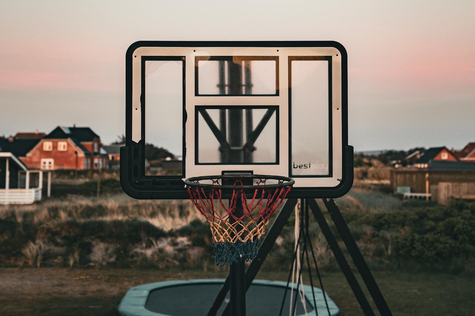 Kosz do koszykówki z kolorową siatką w ogrodzie o zachodzie słońca